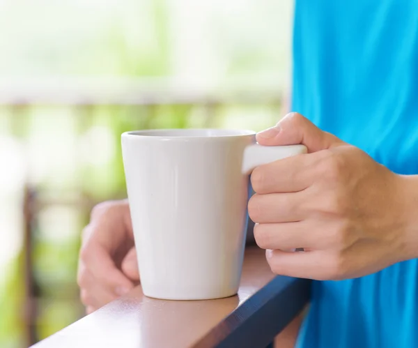 Jovem mulher de vestido azul desfrutando de uma caneca de bebida — Fotografia de Stock