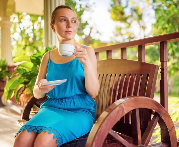 Mujer joven en vestido azul disfrutando de una taza de bebida —  Fotos de Stock