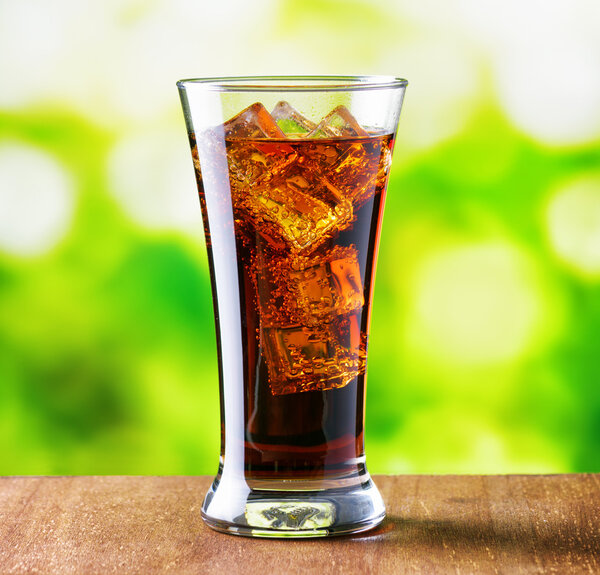 Glass of cola with ice on nature background