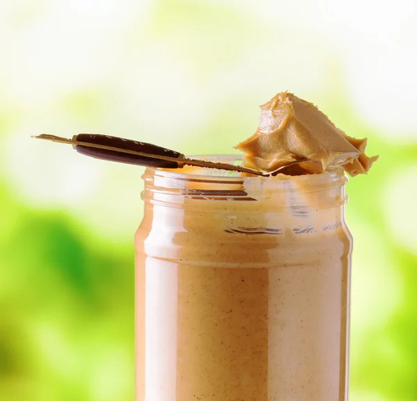 Jar of peanut butter on nature background — Stock Photo, Image