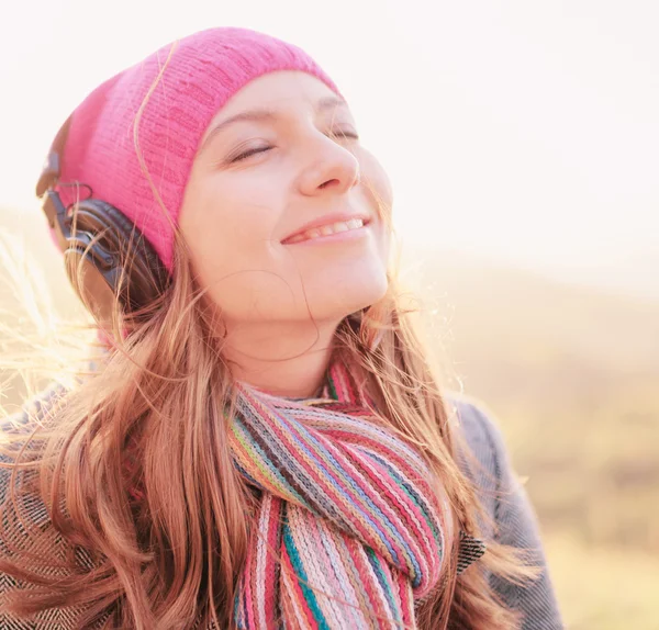 Молодая женщина улыбается, наслаждаясь музыкой в весенний сезон — стоковое фото