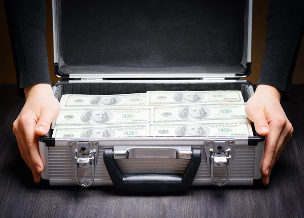 Business man opens an aluminum briefcase full of stacks of hundr — Stock Photo, Image