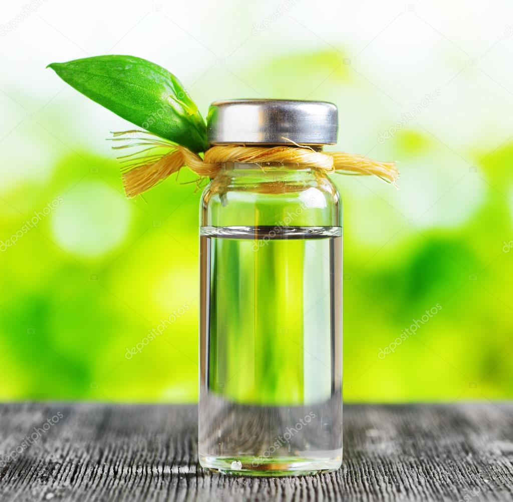 Vial of liquid on a black wooden table and on nature background