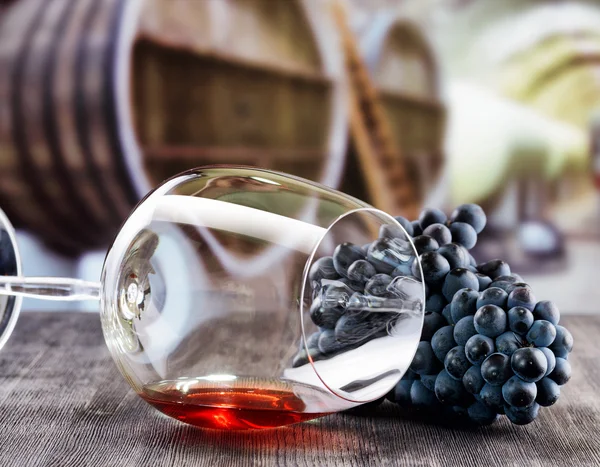 Trauben und ein Glas Rotwein liegen auf einem schwarzen Holztisch. — Stockfoto