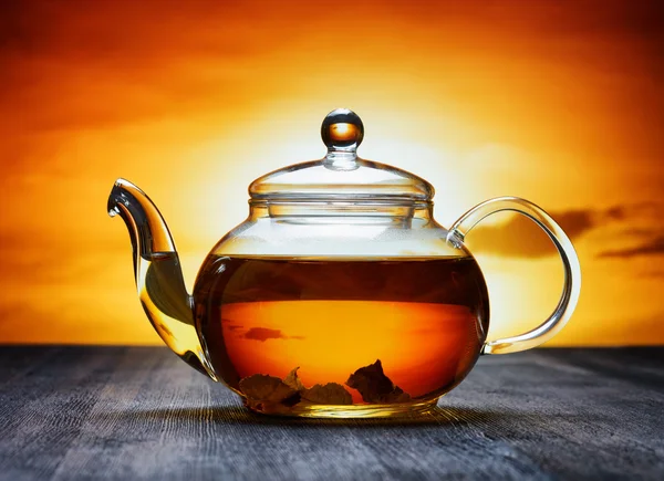 Glas Teekanne mit frischem aromatischen Tee auf einem schwarzen Holztisch und — Stockfoto