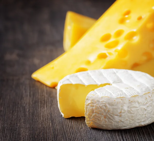 Different types of cheese on a black wooden board — Stock Photo, Image