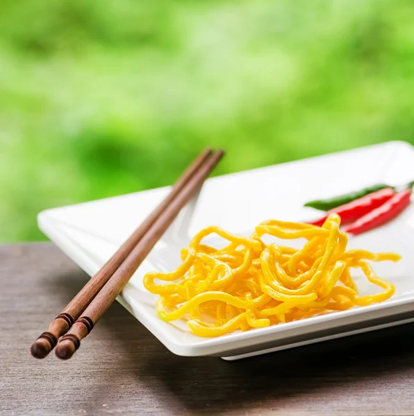 Tagliatelle di uova gialle in un piatto bianco servito con peperoncino — Foto Stock