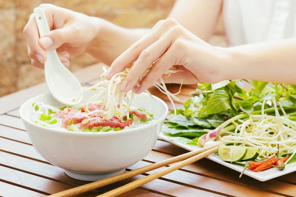 Young woman sprinkles sprouts to the Pho Bo in Vietnamese cafe — Stock Photo, Image
