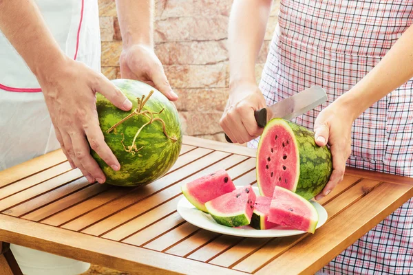 Junge Frau in Schürze schneidet frische Wassermelone — Stockfoto