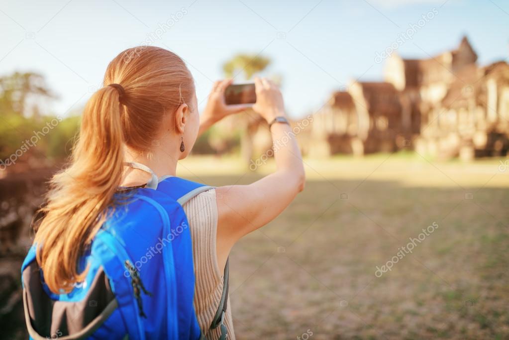 Female tourist taking picture of Angkor Wat temple, Cambodia