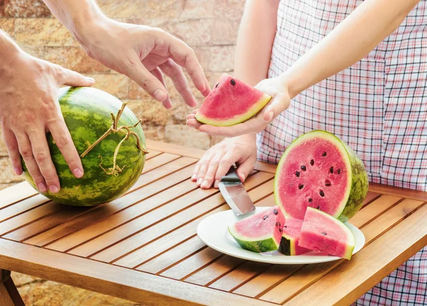 Young woman in apron giving to man slice of fresh watermelon — Stock Photo, Image
