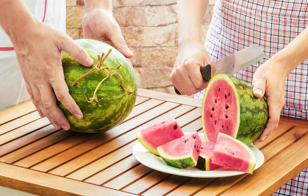 Young woman in apron slicing ripe watermelon — Stock Photo, Image