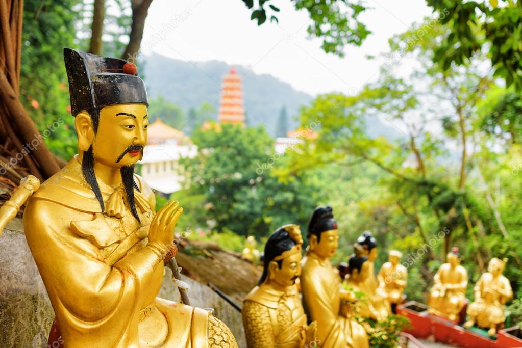 Golden Buddha statues on background of a red pagoda and forest i