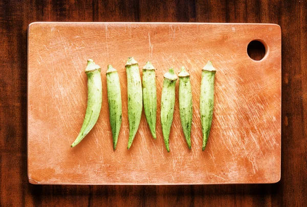 Pods de sementes verdes frescas quiabo em uma tábua de madeira. Eco-alimentação saudável — Fotografia de Stock