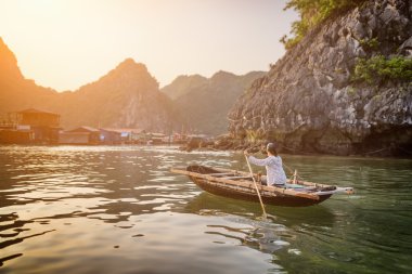 Woman in boat returns to fishing village, Ha Long Bay, Vietnam