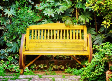 Old yellow wooden bench in garden. Vintage style
