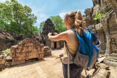 Tourist with smartphone in mysterious ruins of Angkor, Cambodia