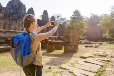 Young female tourist with smartphone in Angkor Thom