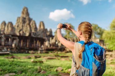 Female tourist taking picture of Bayon temple in Angkor Thom