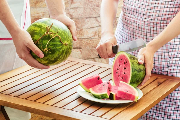 Young woman in apron slicing fresh ripe watermelon — Stock Photo, Image