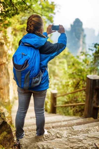 女游客与蓝色背包和智能手机拍照 — 图库照片