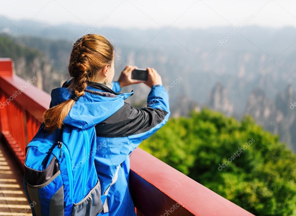 Young female tourist taking photo of scenic mountains