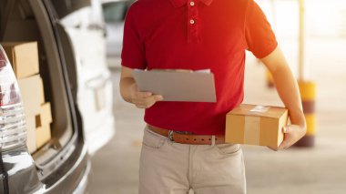 Kırmızı elbiseli, yüz maskeli bir teslimatçı elinde bir paket tutuyor.
