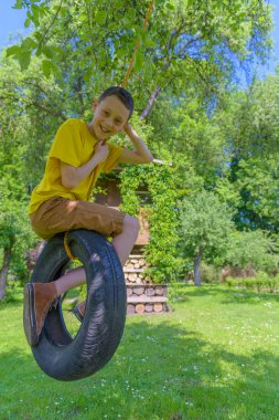 Sarı tişört lastik salıncak üzerinde oynama çocukta gülümseyerek
