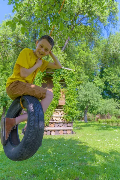 Uśmiechnięty Chłopiec Żółty Shirt Grając Swing Opony — Zdjęcie stockowe