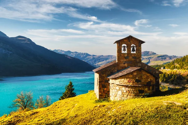 Sunny picturesque view of stone chapel on Roselend lake — Stock Photo, Image