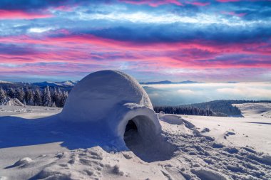 Kış dağlarında akşam güneşinde parlayan gerçek bir eskimo evi.