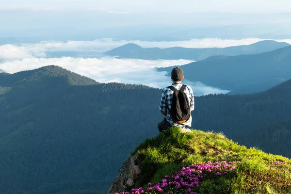 En turist sitter på kanten av en klippa — Stockfoto