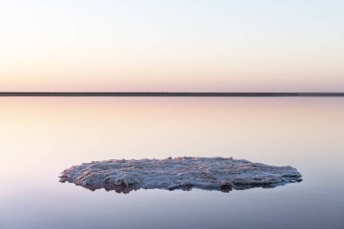 Pembe tuz gölünün pürüzsüz yüzeyine sahip sakin minimalist bir manzara.