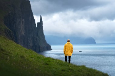 Sarı ceketli turist Cadıların Parmak Uçurumlarına bakıyor