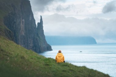 Sarı ceketli turist Cadıların Parmak Uçurumlarına bakıyor