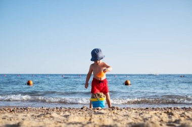 Yaz plajında kırmızı şortlu bir çocuk.