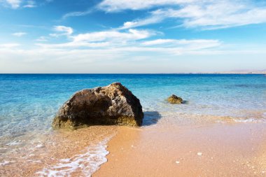 Tropikal kumsalda dalgalar ve mavi okyanusta