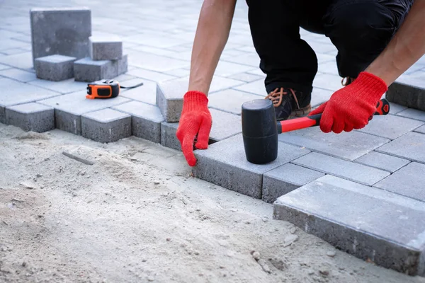 The master in yellow gloves lays paving stones — Stock Photo, Image