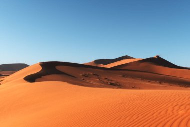 Namib çölünde turuncu kum tepeleri ve açık gökyüzü