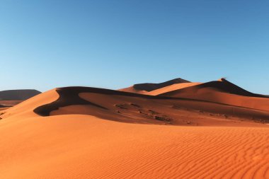 Namib çölünde turuncu kum tepeleri ve açık gökyüzü