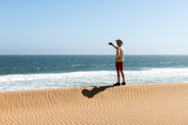 Kovboy şapkalı bekar adam Namib çölünde selfie çekiyor.