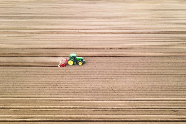 Tractor solitario en el campo agrícola con hileras de tierra arada —  Fotos de Stock