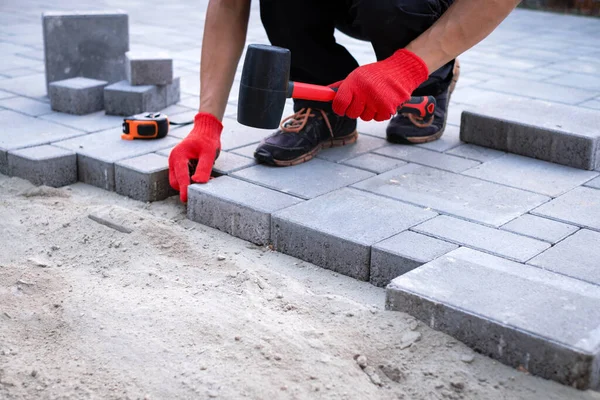 The master in yellow gloves lays paving stones — Stock Photo, Image