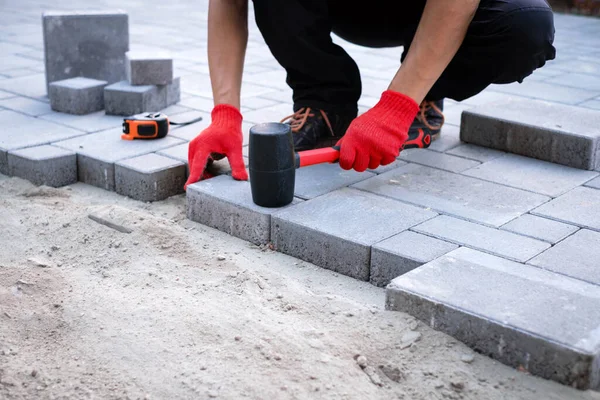 The master in yellow gloves lays paving stones — Stock Photo, Image