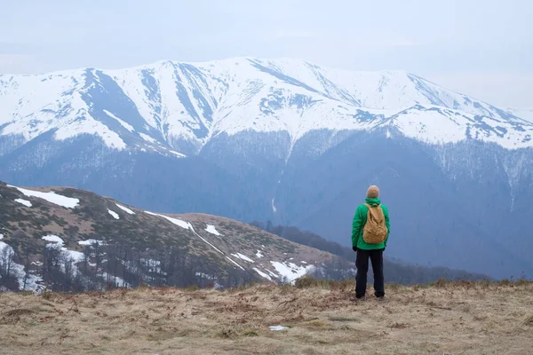 Чоловік з рюкзаком у весняних засніжених горах — стокове фото