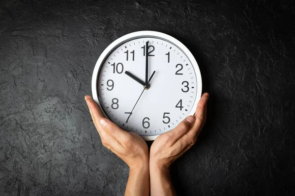 Hand holding clock on black background — Stock Photo, Image