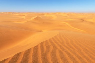 Namib çölünde turuncu kum tepeleri ve açık gökyüzü