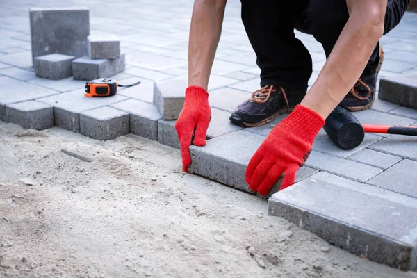 Le maître en gants jaunes pose des pavés — Photo