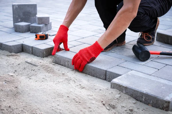 The master in yellow gloves lays paving stones — Stock Photo, Image