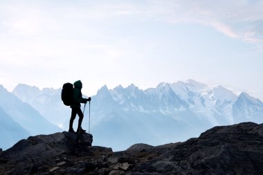 Sırt çantalı yalnız gezgin, karlı dağların önünde duruyor. Keşif ve özgürlük kavramı